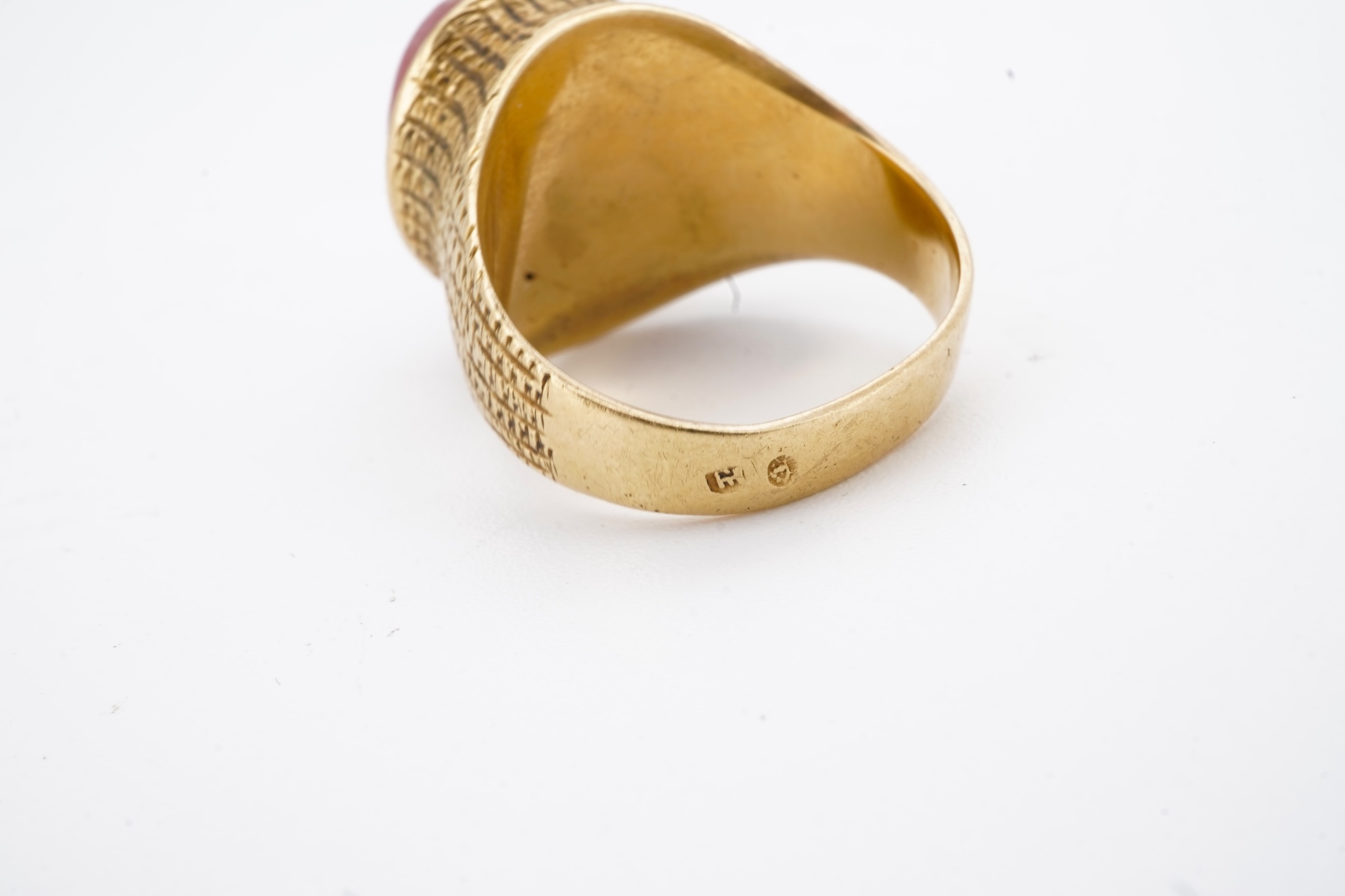 A continental textured yellow metal and cabochon rose quartz set ring, size N/O, gross weight 8.2 grams.